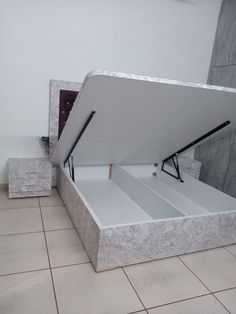 an open white box sitting on top of a tiled floor next to a counter with drawers