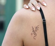 the back of a woman's shoulder with a dragon tattoo on her left arm