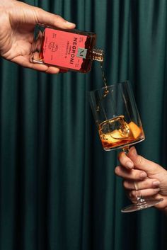 two people are pouring whiskey into glasses