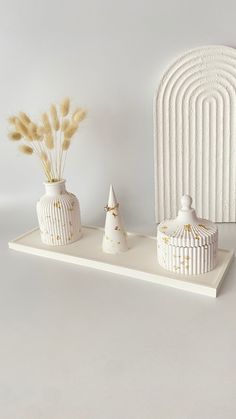 two white vases sitting on top of a shelf next to a decorative piece that looks like a birdcage