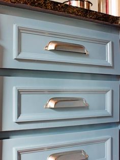 the drawers in this kitchen are painted blue and have brass pulls on them to match the cabinets