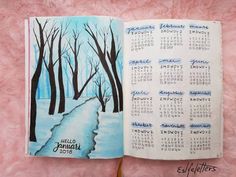 an open calendar book on a pink surface with trees in the background and snow covered ground