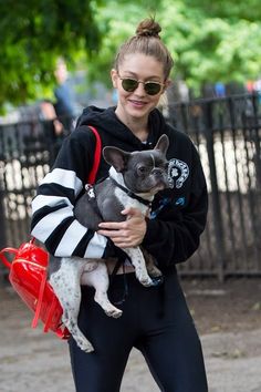 a woman holding a small dog in her arms while wearing black and white striped hoodie