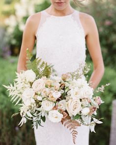 a woman holding a bouquet of flowers in her hands and wearing a white wedding dress