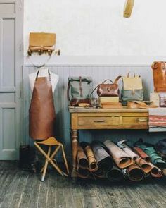 a wooden table topped with lots of purses and handbags next to a wall