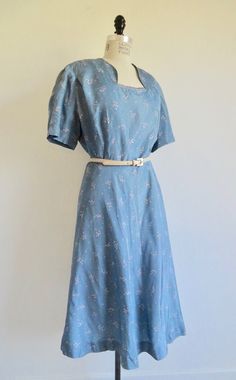 "This 1940's to early 50's dress has a pretty Spring taffeta print of pink and white dots on a dusty blue background. Rare larger size. Bodice has sweetheart style neckline with small fabric tabs at the bottom opening for decoration. Princess line darts for shape and a pleat at the front shoulder edge as well as short sleeves. Set in waist. Mid calf gored flared skirt. Unlined. Side zipper closure. **I am including the contemporary ivory leather belt with purchase. Label: A Lady Petite Condition Blue Vintage Dress With Fitted Bodice, Spring 1950s Style Knee-length Vintage Dress, Vintage Square Neck Dress For Garden Party, Fitted Vintage Blue Vintage Dress, Retro Vintage Dress For Spring Events, Blue Vintage Summer Dress, Summer Vintage Blue Dress, 1950s Style Tea Length Vintage Dress For Spring, 1950s Style Spring Tea-length Vintage Dress