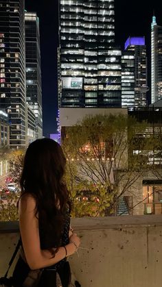 a woman sitting on a ledge looking at the city