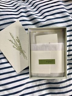 an open box with some papers in it sitting on a bed next to a blue and white striped blanket