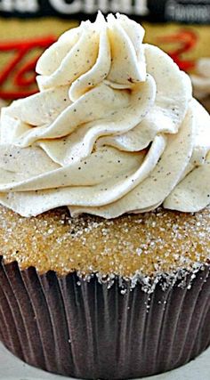 a cupcake with white frosting and sprinkles on top sitting on a plate