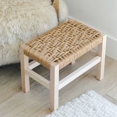 a wicker stool sitting on top of a wooden floor next to a white rug