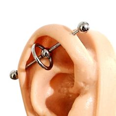 an ear with two piercings attached to it's sides and one has three balls in the middle