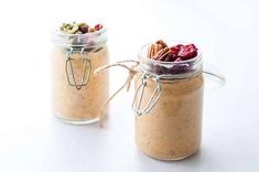 two jars filled with food sitting on top of a white table next to each other