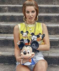 a woman sitting on some steps holding a mickey mouse