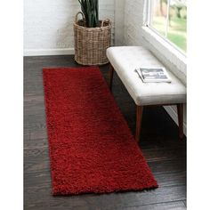 a long red rug in front of a window next to a white bench and potted plant