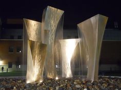 three water fountains in front of a building at night