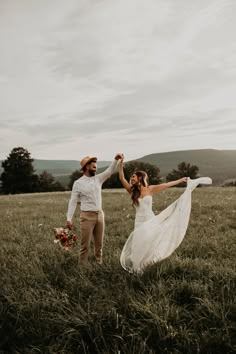 a bride and groom holding hands in a field