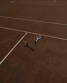 two tennis rackets laying on the ground in front of an empty court with no people