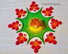 an intricately designed rangolii with red and orange flowers on white wooden background