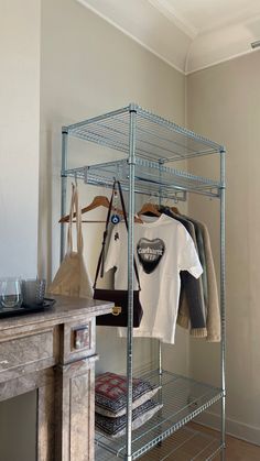 a closet with clothes and ironing board on the floor next to a table in front of it