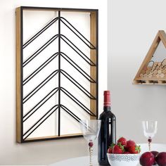 a wine bottle and two glasses sitting on a table next to a shelf filled with fruit