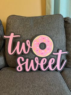 a pillow that says two sweet with a donut on it sitting on a couch