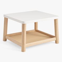 a white coffee table with wooden legs and a shelf underneath it for storage or display