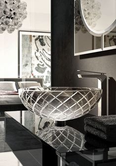 a glass bowl sitting on top of a black table next to a mirror and chair