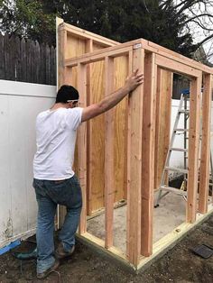 a man standing in front of a building with wood framing on the side and walls