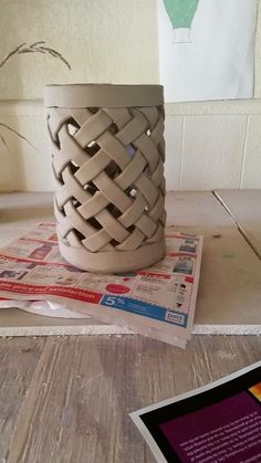 a white vase sitting on top of a table next to a pile of paper and scissors