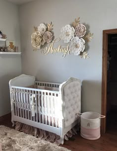 a white crib with flowers on the wall next to a baby's bed