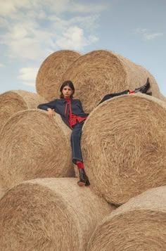 a woman sitting on top of hay bales