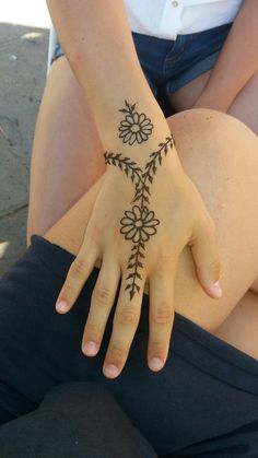 a woman's hand with a tattoo on it and flowers in the middle of her arm