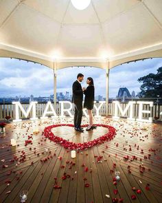 two people standing in front of a sign that says marry with rose petals on the floor