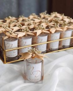 several small candles with bows are sitting on a gold tray that is filled with flowers