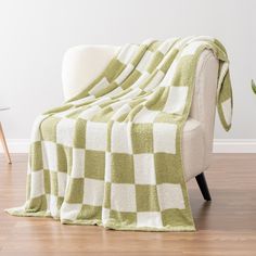 a green and white checkered blanket sitting on top of a chair next to a potted plant