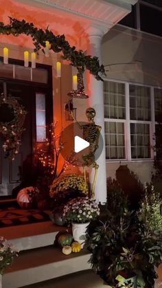 the front porch is decorated for halloween with pumpkins and greenery on display at night