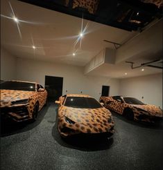 three cars in a room with leopard print covering them, and lights on the ceiling