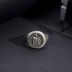 a silver ring with an image of jesus on it sitting in front of a black background