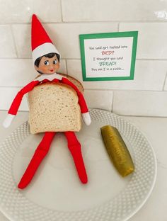 an elf is sitting on a plate with bread and pickle in front of him