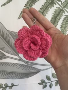 a hand holding a pink crocheted flower keychain