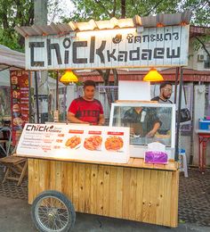 a man standing behind a food cart at an outdoor market