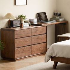 a bed room with a neatly made bed and a laptop on top of the dresser