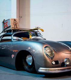 an old silver sports car with a surfboard on top