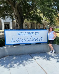 a woman standing in front of a welcome sign with the words, welcome to louisiana