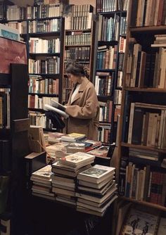 a woman standing in front of a bookshelf filled with lots of books on top of shelves