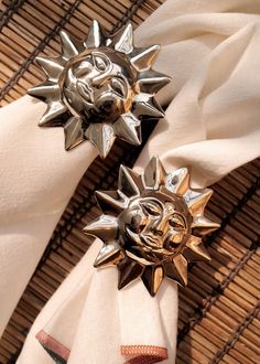 two napkins with metal sun decorations on top of them, sitting next to each other