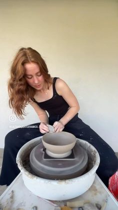 a woman is making a bowl out of clay