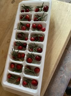 an ice tray filled with cherries on top of a wooden table