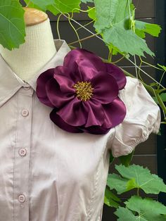 a white dress with a purple flower on the front and side, sitting next to green leaves