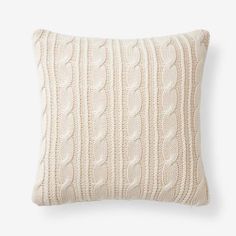 a white cable knit pillow on a white background